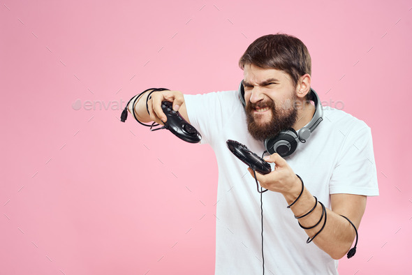 Man with joysticks in hands headphones fun emotions game pink background