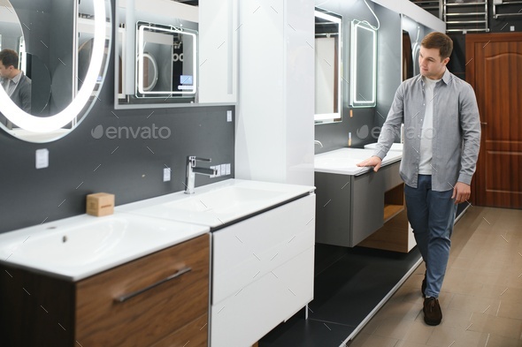 Man choosing new bathroom furniture at the plumbing shop with lots of sanitary goods