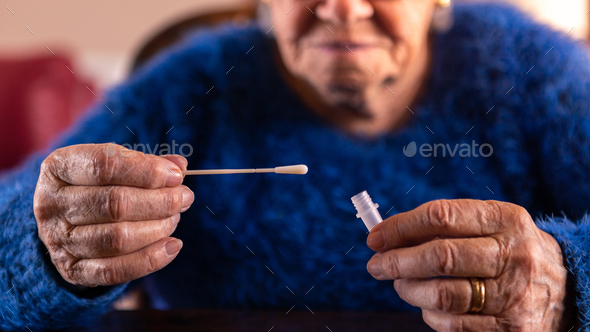 Old woman holding a cotton swab for nose to collect a possible positive COVID-19