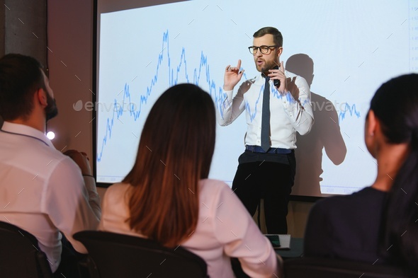 Trading teaching. Male leader talking to employees, showing the plan on the projector in office