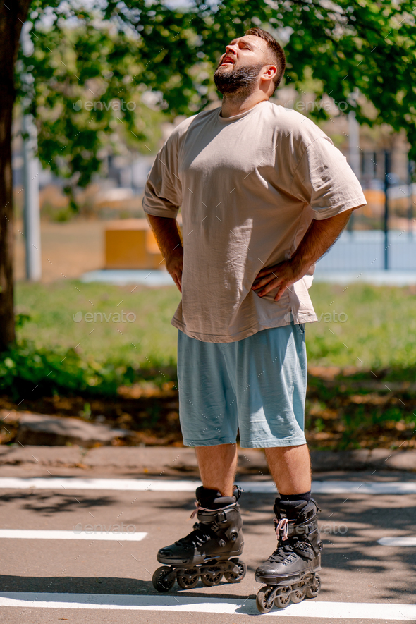 Portrait of young guy tired of rollerblading against the background of