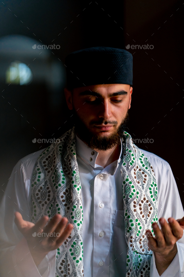Portrait of a Muslim man praying on his knees in Ramadan and giving thanks for support and spiritual