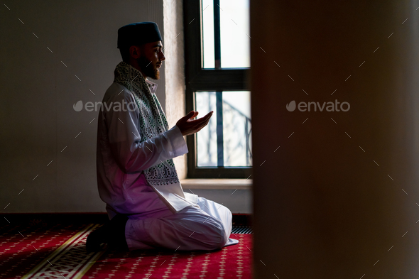 Muslim man prays on his knees in Ramadan and thanks for support and spiritual well-being
