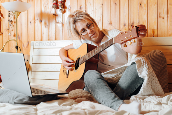 Adult caucasian woman musician studying on laptop an online acoustic guitar music course