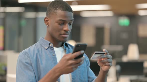 Young African American Man Making Online Payment on Smartphone alt