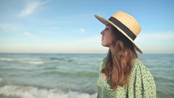 Romantic Portrait of Attractive Caucasian Young Woman in Green Dress and Straw Hat on the Seashore alt