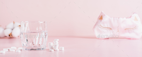Good sleep concept, sleeping pills, glass of water and sleep mask on pink web banner
