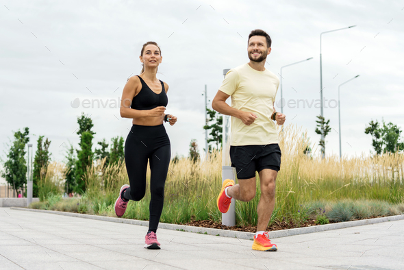 Active couple running in sync, enjoying a healthy lifestyle in an urban ...