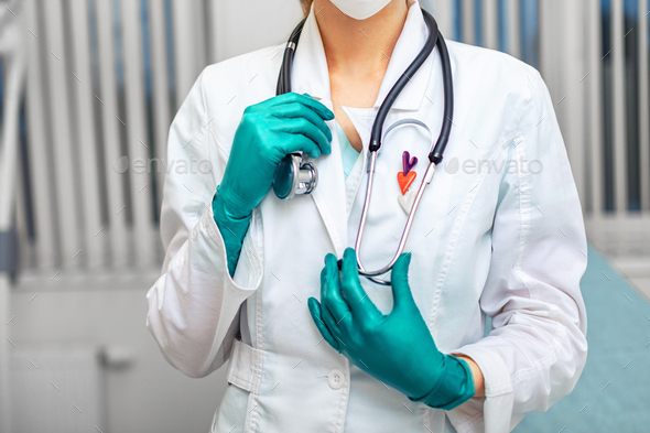 Doctor\'s hand in white coat holding a phonendoscope on the background of a hospital ward. Medicine