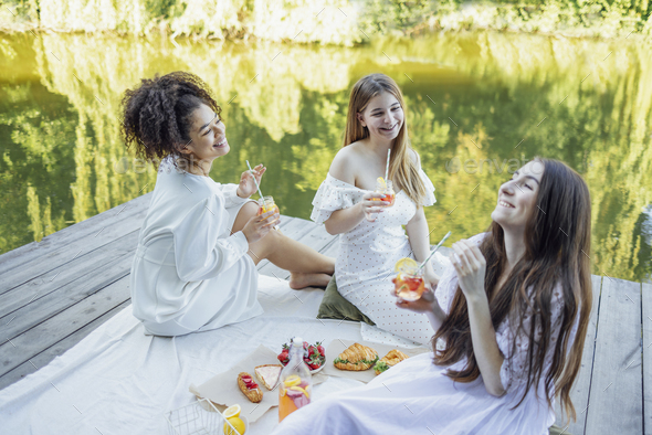 Happy female friends on picnic on the bank of a river