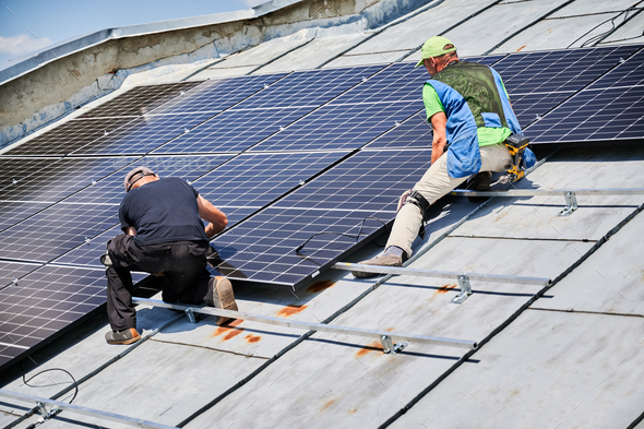 Workers building solar panel system on roof of house. Men installing photovoltaic solar module