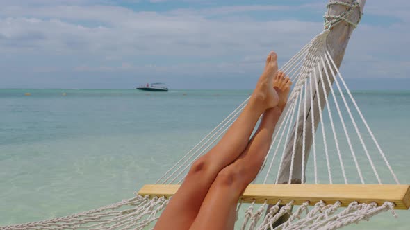 Woman in White White Bikini Relaxes in a Hammock Over Turquoise Tropical Waters alt