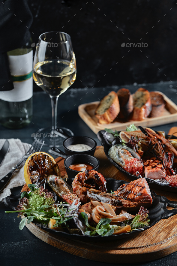 Fresh seafood and white wine on a stone table. Oysters, prawns and scallops, squids, served by the
