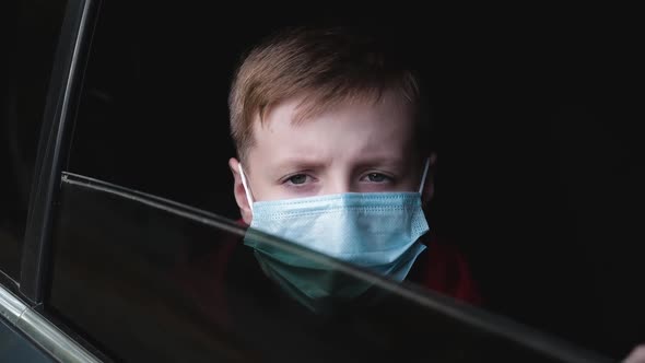 Young Boy in a Medical Mask Waving Goodbye Through the Car Window and Lifts the Glass.