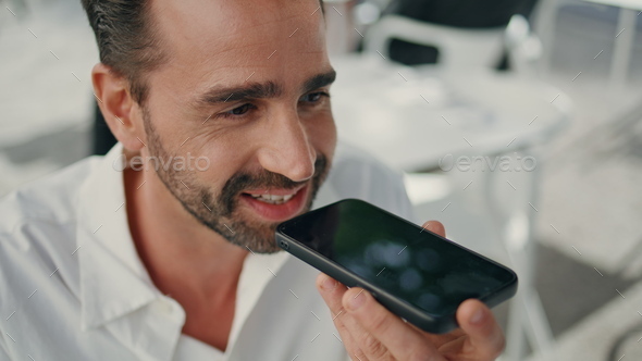 Closeup businessman send voice mail using cellphone in terrace. Smiling man talk