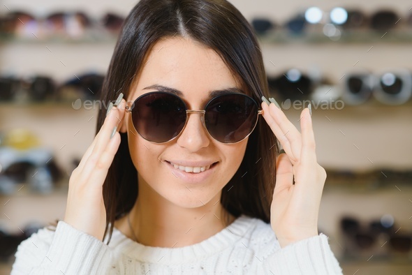 Which one is better fit me. Portrait of cheerful hesitating woman in optician store