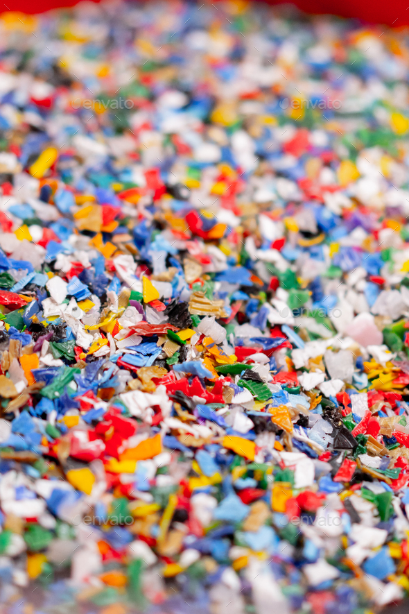 Close-up shot of shredded plastic caps stored in a special container at waste recycling station