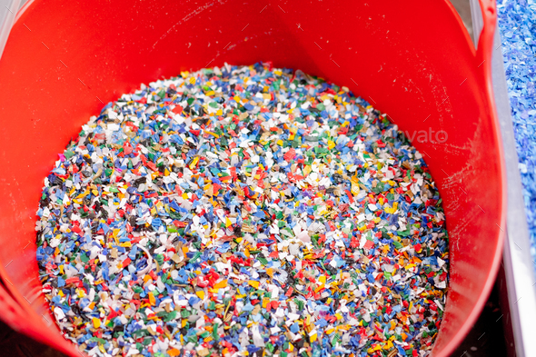 Close-up shot of shredded plastic caps stored in a special container at waste recycling station