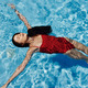 Happy woman swimming in the pool in red swimsuit with loose long hair  relaxed in the sunshine, skin Stock Photo by shotprime