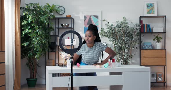 Influencer with Black Dreadlocks Sits at Desk in Room Prepared to Record Videos for Social Media alt
