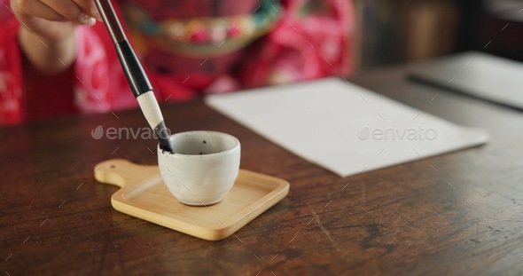 Ink, writing and hands of Japanese woman in home for traditional script on paper, documents and pag