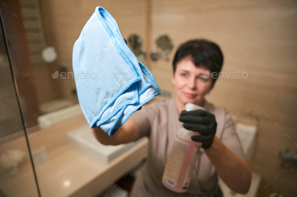 Maid in disposable gloves is cleaning hotel bathroom
