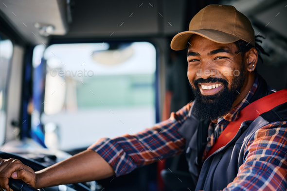 Happy black professional truck driver looking at camera.