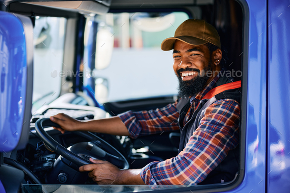 Happy black driver driving his truck and looking at camera.