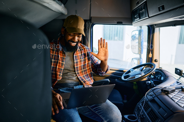 Happy black truck driver making video call from a vehicle cabin.