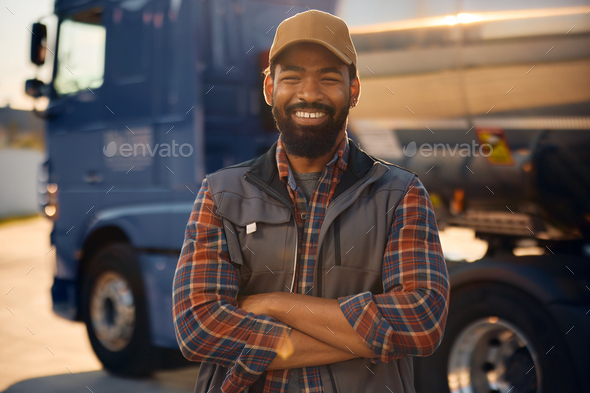 Confident black truck driver in front of his vehicle looking at camera.