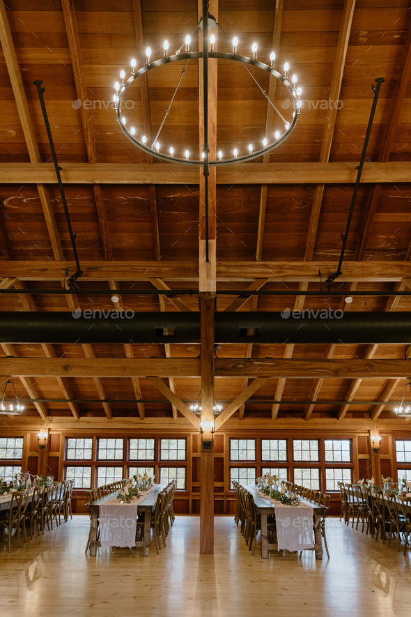 Light fixture hanging from rafter ceiling in rustic barn reception hall ...