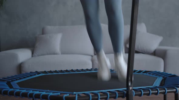 A Woman Trainer Does a Home Workout on a Mini Trampoline
