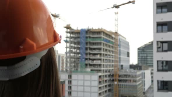 Female Builder at a Construction Site Oversees the Progress of Construction Work