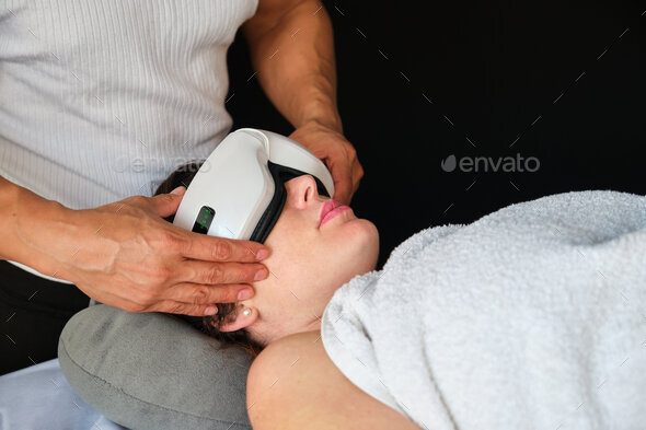 Therapist putting on a woman smart eye massager.