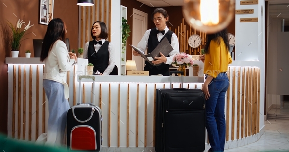 Hotel employees greeting customers at front desk in lobby