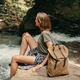 Young female traveler with backpack resting while sitting by the mountain river - PhotoDune Item for Sale