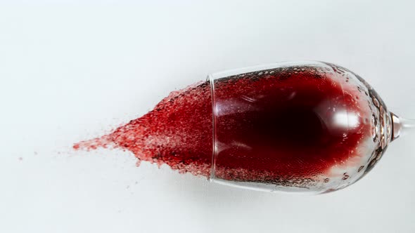 Super Slow Motion Top Shot of Falling Glass with Red Wine on White Cloth at 1000Fps. alt