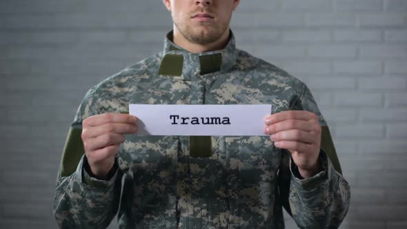 Trauma Word Written on Sign in Hands of Male Soldier, Damage to Body, Health alt