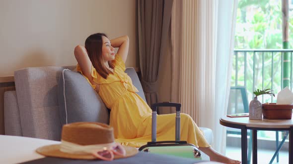 Young woman traveler sitting and relaxing in a hotel room while on summer vacation