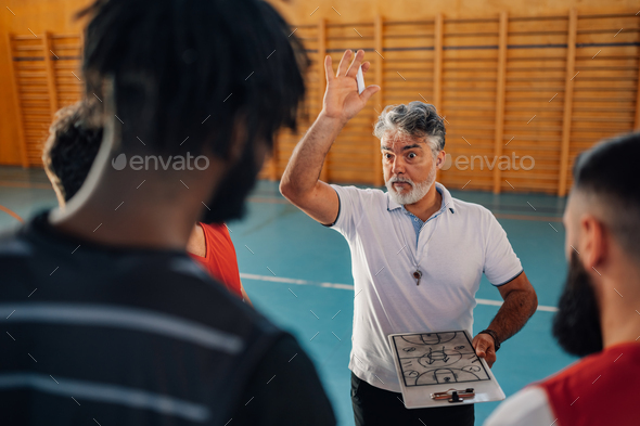 A senior basketball trainer discussing game plan with his team.