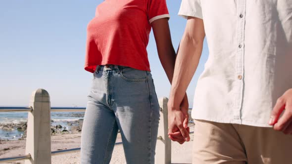 Couple holding hands and walking on beach promenade 4k alt