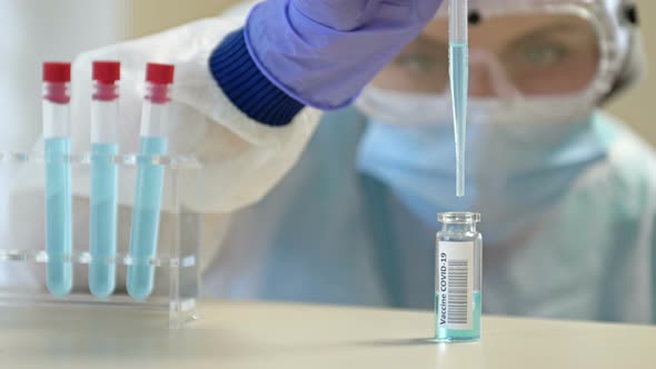 Professional Female Scientist in Protective Eyeglasses and Mask Making Experiment with Reagents in alt