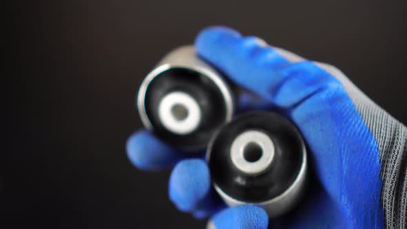 master in glove holds lever silent block in his hand against background engine. alt