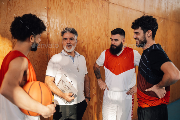 An interracial basketball team is discussing with their senior coach.