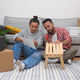 happy couple in new apartment builds modern wooden shelf unit surrounded by boxes, home decor - PhotoDune Item for Sale