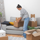 single woman relocates to new home, bringing cardboard boxes into living room - PhotoDune Item for Sale