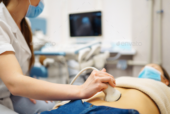 Doctor makes patient women abdominal ultrasound. Ultrasound Scanner in hands of doctor. Diagnostics.