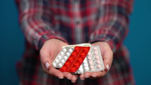 Woman Presenting a Handful of Foil-wrapped Pills alt