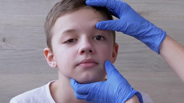 Pediatrician in Latex Nitrile Gloves Examines Eyeball Teeth Mouth of a Boy alt