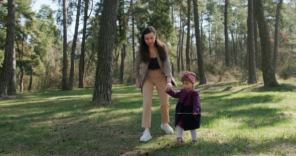 Happy Little Girl Walking and Playing with Mother Among Trees in Coniferous Forest, Healthy Child alt